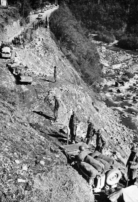 Climbing a Mountain in Italy: Working their way up a newly repaired mountain road southwest of Bologna, Italy, U.S. jeeps and trucks pass American troops who stand by to aid any vehicle that lags. The men and vehicles are part of the Allied Fifth Army, which was proceeding slowly toward Bologna over muddy, hear-breaking terrain late in October, 1944. The Germans had massed artillery and were erecting additional barbed wire barriers, to hamper the advance further. November 22, 1944. (Photo by U.S