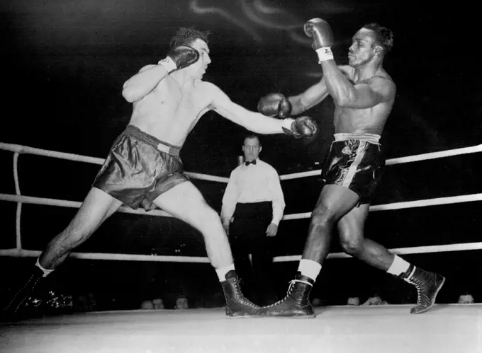 Duke Of Edinburgh at Harringay Boxing Tournament -- Johnny Williams misses with his left as Agramonte sways back. Johnny Williams (Britain) V. Omelio Agramonte (Cuban Heavyweight Champion) at Harringay to-night. December 04, 1951. (Photo by Paul Popper)