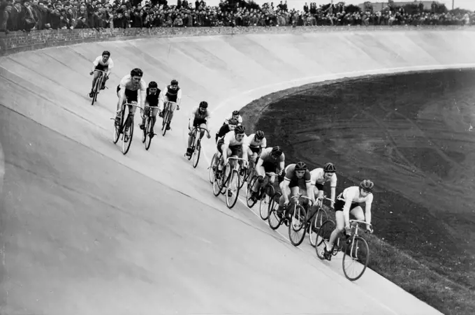 Progress of Britain's New Sport - Cyclists competing at a meeting of the Manchester Track Racing League on the new Fallowfield track, as an excited crowd lines the top of the banking. A cinder track for foot events can be seen on right. It is expected that all existing British cycle records will be broken on the new Continental-style track now in use at Fallowfield, Manchester. It is to be opened officially next month, when cycling stars from all over Europe will compete. The tracks, with steep 