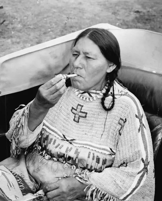 The End of A Perfect day -- Red Cloud Woman Lights her Cigarette with the lights from the swanky car they rented for the occasion and their Trip to tow. January 11, 1941. (Photo by Associated Press Photo).;The End of A Perfect day -- Red Cloud Woman Lights her Cigarette with the lights from the swanky car they rented for the occasion and their Trip to tow.