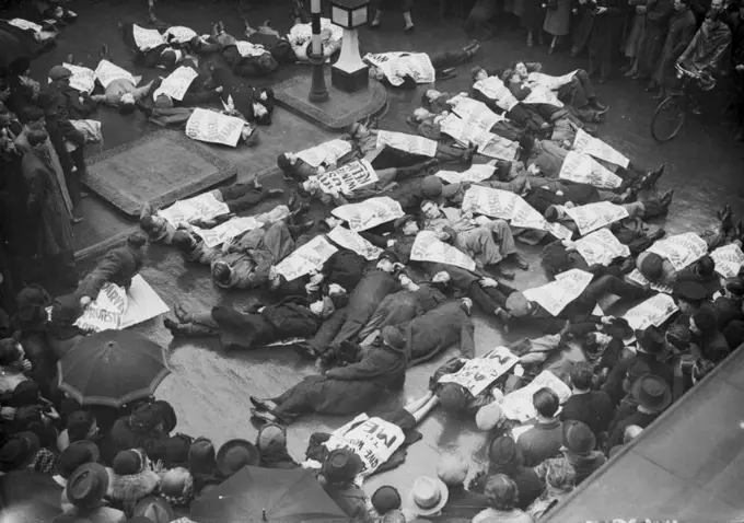 Unemployed "Lie-Down" Demonstration In Oxford-Street -- The unemployed during their "lie-down" demonstration in oxford-street this afternoon. Jan. 14. Unemployed demonstrators have been staging various "scenes" to draw attention to their claims for winter relief shortly before Christmas a number of men lay down in the snow at oxford-circus. Another exploit was to order tea aft the Ritz Hotel. (Jan-17), a large number of unemployed lay down on their backs in oxford-street in the heavy rain, while women paraded the pavements with posters. January 17, 1939. (Photo by Associated Press Photo). 