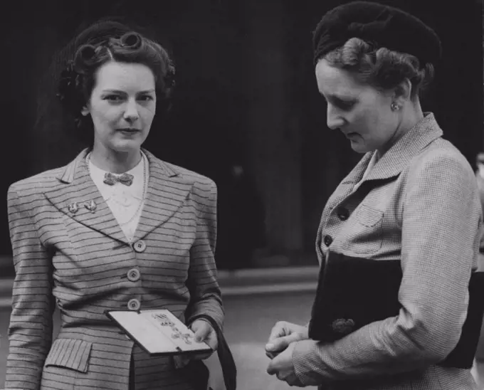 At a recent Investiture held by the King -- Mrs. Collyns (left) with the DFC awarded to her late husband, F/LT. Basil Collyns, of the Royal New Zealand Air Force, after receiving the decoration form the King. On right decoration from the King. On right is her mother in-law, Mrs. Uollyns. March 26, 1945. 