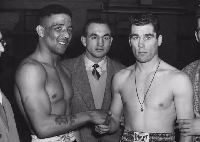 Weigh-in For The Big Fight. A shake-hands at their Solomon's Gymnasium weigh-in to-day (Tuesday) between Britain's Randolph Turpin and America's Walter Cartier (Right) who meet to-night at London's Earl's Court. Looking on in centre is Charles Humez, French middleweight, listed as Turpin's world-title opponent at the White City on June 9th. He will be watching the fight to-night. On the right is Vince Cartier, Walter's lawyer-brother. March 17, 1953. (Photo by Planet News Ltd.).