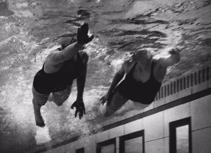 Under water picture taken through the observation panels at Loughborough College, Leicester, showing Fearne Ewart (16) of St. Leonards the 100 yards Junior Free Style Champion and Valerie Nares-Pillow of Kingston on Thames the Junior 220 yards Free Style Champion. April 16, 1953. (Photo by Daily Mirror).