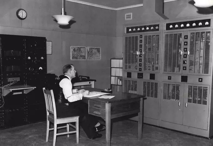 Main transmitter and speech input equipment. In right is transmitter which is self contained unit. Safety doors ***** automatically cut off high high tension to transmitter when opened. Technician G. Oswald enters up details in log. July 1, 1951.