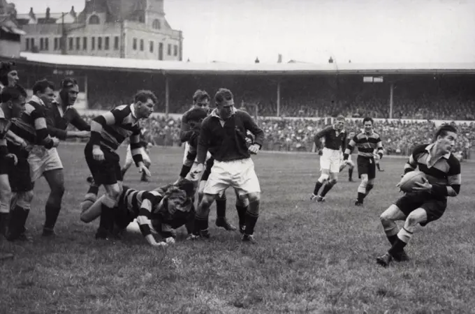 South Africans Win At Cardiff -- J.D. O'Brien (Cardiff - on ground in skull-cap) gets the ball to R. Willis who starts a three-quarter movement. After a stern battle the South African Springboks won their match against Cardiff- at Cardiff - by 11 points to 9. October 20, 1951. (Photo by Sport and General Press Agency, Limited).