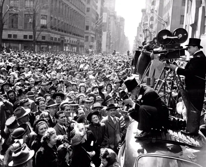 Formal Attire Is The Keynote -- Formal attire is the keynote for Paramount newsreel photographers Al Mingalone (operation hand camera) and Doug Dupont (on movie camera standing), as they catch the crowd and spirit of Easter Sunday along fifth avenue, New York City, during the citys traditional easter parade. March 28, 1948. (Photo by Associated Press Photo).