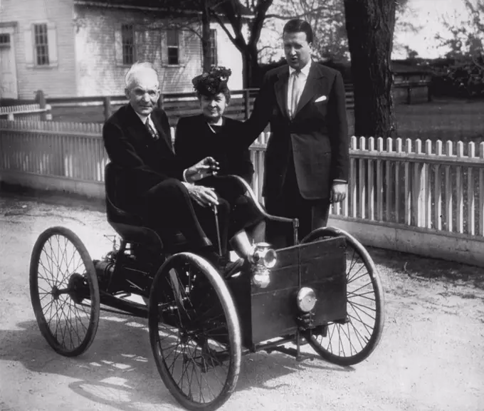 Ford Rides In His First Car -- Sitting in the first machine he built (in 1896) is Henry Ford founder of the Ford Motor Co., who is preparing for the celebration of Detroit's automotive golden jubilee, which will honor him and other auto pioneers. Mrs. Ford sits beside him. Standing at right is Henry Ford II, President of Ford Motor Co. May 25, 1946. (Photo by  Associated Press Wirephoto).