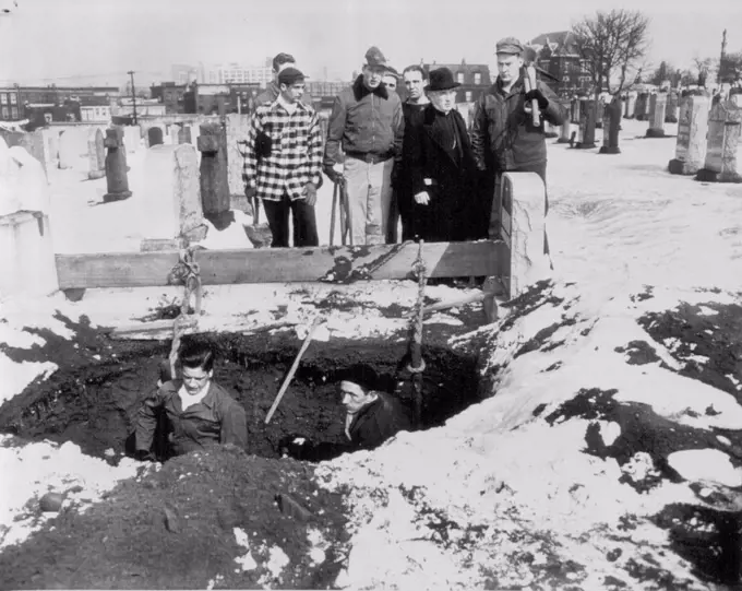 Seminarians Dig Graves -- With Francis Cardinal Spellman as overseer, candidates for the priesthood from St. Joseph's Seminary, Dunwoodie, N.Y., look on today as two fellow students, John Donohue (left) and Kevin Flynn dig grave in strike-bound Calvary cemetery, Queens. Cardinal Spellman asked the seminarians to dig the graves after more than 600 bodies remained unburied. Union gravediggers continued to picket the burial ground as the volunteers entered the cemetery and went to work. March 03, 1949. (Photo by AP Wirephoto).