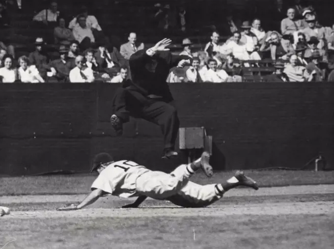 Physically as well as spiritually, umpires risk a beating. In this picture an agile umpire is avoiding being knocked about by a diving base runner. Umpires run the risk of being cut by illegal tips worn by players. May 1, 1952. (Photo by Look Magazine).
