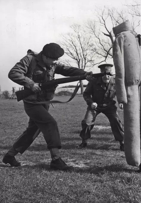 Soldiers In Training -- Spurred on by his instructor Q.M.S.I. Mackenzie, one of the senior instructors at the School, Pte. Brian Hulbert from Chippenham (Wilts) is seen engaged in bayonet practise during training in the small Arms Wing of the School of Infantry, Hythe (Kent). The Small Arms Wing of the School of Infantry at Hythe (Kent), is a development from the old School of Musketry. It's main purpose is the training of picked N.C.O.'S and Privates, both Regulars and National Servicemen, for an intensive course in the handling of all the small arms, which a modern infantryman may be called upon to use. April 28, 1954. (Photo by Fox Photos).