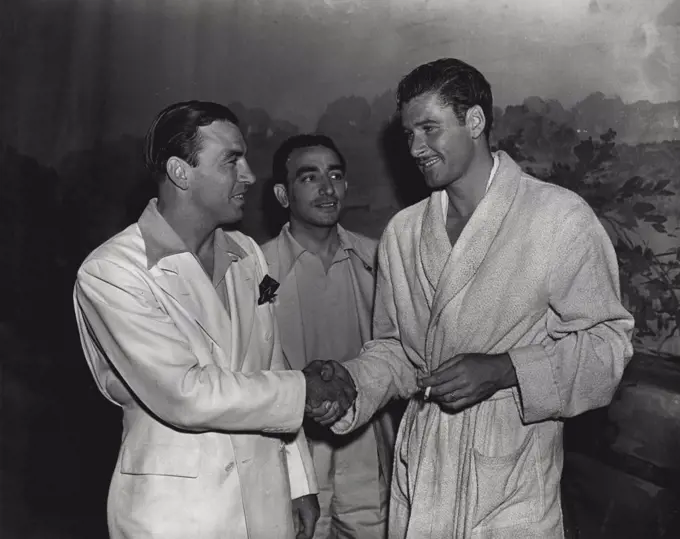 A star of the roped square meets a star of the silver screen -- Ken Overlin, American boxer, who will fight Fred Henneberry at the Stadium next Monday night, meets Errol Flynn, Australian movie actor, during a visit to Hollywood. Chris Durdie, Overlins' manager, looks on. May 26, 1938.