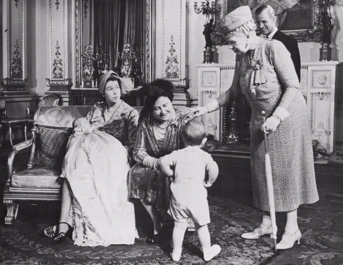 The Little Prince Who Wouldn't Join Royal Group - Queen Elizabeth and Queen Mary, right, try to talk the little Prince into turning round and face the cameras, while the Duke of Edinburgh seems to be enjoying the Prince's boyish pranks. His mother, Princess Elizabeth (holding Princess Anne) tends to make a sterner view.Prince Charles, now nearly two, already has a will of his own. When the Royal Family assembled in the blue drawing room of Buckingham Palace, London, for photographs to be taken following the christening of his little sister, Princess Anne, the Prince just refused to pose. After he had been persuaded to joint the Royal group he scampered away again, slid on the polished floor and took refuge behind a settee. October 23, 1950. (Photo by Paul Popper Ltd.).