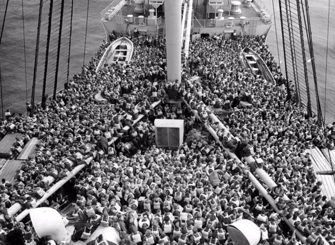 The Queen Mary On War Service -- Scene during a crossing of the Atlantic, when the Queen Mary was Britain bound. Troops massed on deck practice boat drill.The greet British Atlantic line Queen Mary has a fine wartime record as a troopship. December 01, 1944. (Photo by British Official Photograph).
