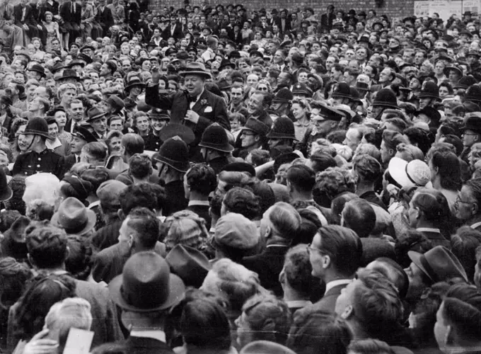 Churchill Hailed On Election Tour -- The Prime Minister stands in the leading car of a long procession passing through densely-crowded/Trinity-street, in blitzed Coventry, where he received a great ovation from the people. Making a ten-speeches-a-day election tour, Mr. Churchill, Conservative leader, ended the first day in the Midlands tired but triumphant, his campaign taking on the appearance of a victory celebration, with men and women of all political parties thronging the route to cheer the leader of the Coalition Government which led Britain to victory in Europe. June 26, 1945. 