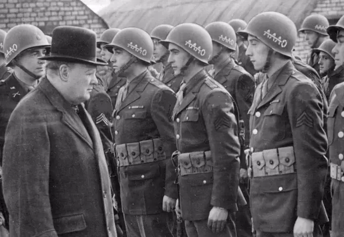 Passed By The Censor - Premier Reviews Second Front U.S.Troops.Mr. Churchill inspecting American infantrymen. On their steel helmets is A.A.A.O. with Bar, which means anywhere, anytime, anyhow, bar nothing.Mr.Churchill accompanied by the Supreme Commander, General Eisenhower, continued for the second day his review of second front U.S. Forces in Britain when he inspected  a cross-section of the whole American Army and addressed the soldiers. June 06, 1944. (Photo by Associated Press Photo).