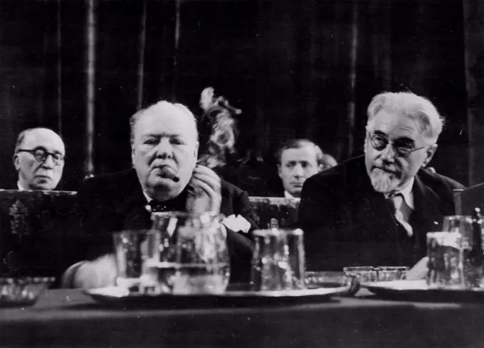 Churchill Concentrates On European Union Inaugurates Hague Congress.The Hague - Smoke curls from Winston Churchill's fat cigar as, seated behind water carafe and glasses, he apparently concentrates on the speech he was to deliver at the inaugural meeting of the Congress of Europe in the hall of knights in the Dutch capital with him is the former socialist premier of France, M. Paul Ramadier.Churchill was wildly acclaimed by delegates of 23 nations including the 16 in the Marshall Plan - when he called for the immediate establishment of a European Assembly and asked: 'Shall so many millions of humble homes in Europe sit quaking in dread of the policeman's knock' The Congress, he declared, must be a movement of peoples not of parties -"it must be all for all'. May 08, 1948.