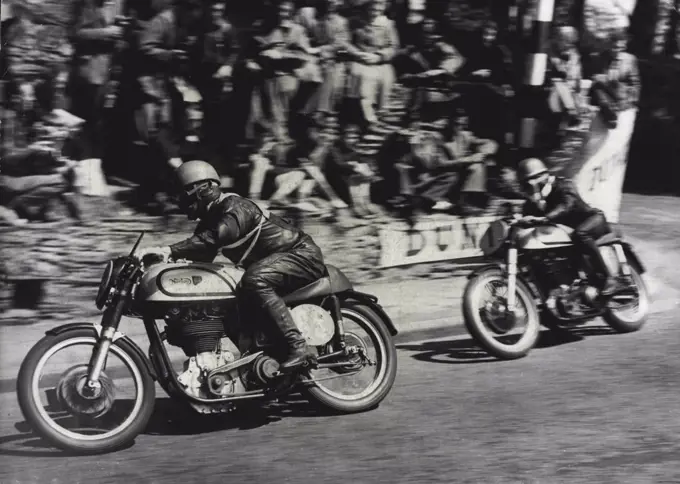 Motor Cycling "Duke" Wins Isle Of Man Race -- Geoffrey Duke riding a Norton (No.1) catching up on T. McEwen (also on a Norton) (No. 85) around the sharp corner at Governor's bridge during the race.Geoffrey Duke - "The Duke" of motor cycle racing - won the Senior International Tourist Trophy Race in the Isle of Man yesterday and smashed all his own records - by mistakes. On his second circuit of the course he misread a signal and thought he was lying third. He "burned up" the last 13 miles of the 38-mile course, touching 130 miles perhour and raised his lap record form 93.53 miles per hour to 95.22. June 9, 1951. (Photo by Paul Popper).