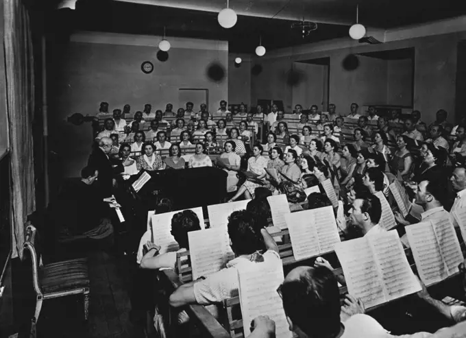 La Scala Strike Ends -- The La Scala choir in rehearsal under its conductor and trainer Veneziani.The Chorus and Orchestra of La Scala, Milan, ended their ten day strike on Wednesday.The strike concerned their right to make recordings. They have agreed to work exclusively for the Opera House from January 1, 1953.Sir Thomas Beecham was to have conducted a concert in La Scala last week but this had to be cancelled on account of the strike. October 17, 1952. (Photo by Paul Popper).