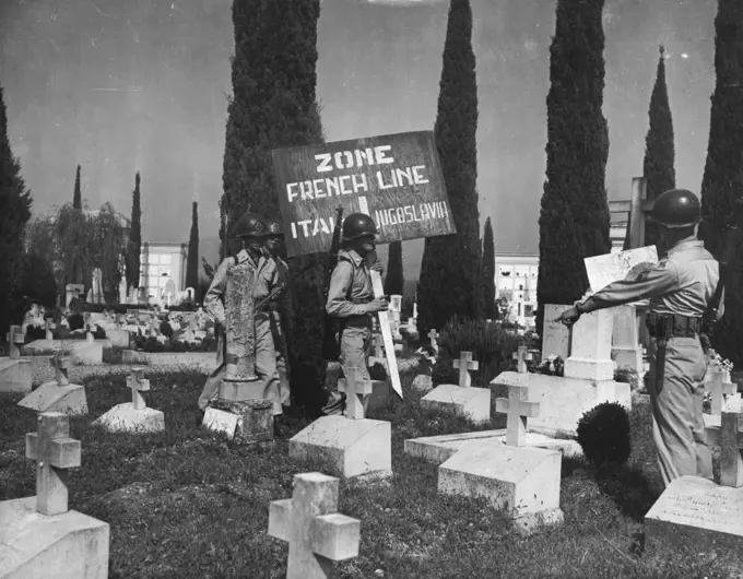 Marking New Italic-Yugoslav Boundary -- Soldiers place a marker in a cemetery on the outskirts of Gorizia, divided by the French Line, September 10. At this point, near Gorizia, Venezia Giulia, West of the "Morgan Line" that the Anglo-American and Yugoslav occupation areas of the once completely Italian province of Venezia Giulia, were divided.Graves in foreground are thoge of Italian soldiers who died in World War II.Soldiers in picture are from 350th Infantry Regiment, U.S. 88th Division. When instruments of ratification of the Italian Peace Treaty are deposited in Paris, September 15, all British and American Troops will man their new frontier. September 13, 1947. (Photo by Associated Press Photo).