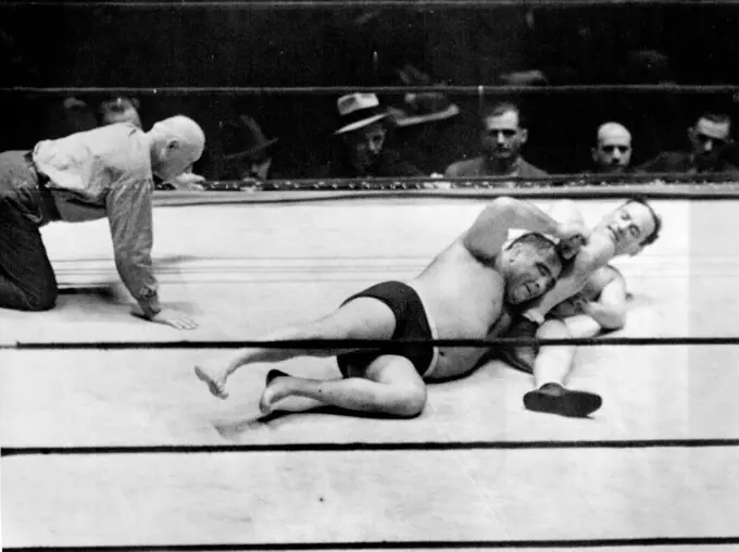 Strangler Lewis Retains Title -- Ed (Strangler) Lewis, World's Heavyweight Wrestling Champion, had no difficulty defending his crown against the assault of Dr. Fred Meyers, Chicago's Rappler-Dentist, in Madison Square garden, New York City, night of February 6. Lewis pinned the shoulders of his Rival in 25 minutes, 27 seconds. In the Above Photograph, thing looked bad for a moment for Lewis, (Left), When Meyers got an Arm lock on the Champion. February 6, 1933. (Photo by Associated Press Photo).