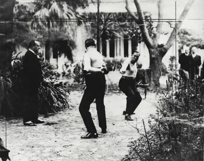 "On Guard" - The rarest of photographs, for South America, is shown above. It is a view of the duel held privately, between senior Manuel Fresco, Jr., and senior Julio V. Rocha, national deputies of Argentine. In our thrilling picture the combatants on the field of honor shown just after the start of their fight. Baron Demarchi is shown at the left, in his role of Judge. After several minutes of lighting-fast sword play, Sr. Fresco wounded Sr. Rocha Twice, in the fore-arm and under the left eye. Baron Demarchi stopped the fuel and surgeons present for this occasion examined ***** Rocha was declared unfit to continue the ***** the adversaries and their seconds bowed to ***** and withdrew from the field of honor, which ***** was the garden of a beautiful residence ***** of Buenos aires. October 27, 1930. (Photo by The International News Photo).