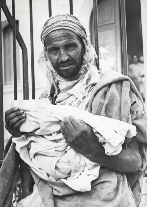 Allied Lend-Lease Goods Distributed In North Africa -- An Arab resident of Zeralda, Algeria, holds the clothing material he has received at the village market where lend-lease goods, sent to North Africa from the U.S. are sold at cost to civilians. The United States shipped more than 170,000 tons of clothing, food and other essentials to French North Africa up to May 31. There, the supplies are made available to the population by the North African Economic Board in co-operation with French governmental authorities under the the Allied program of rehabilitation for liberated areas. November 06, 1943. (Photo by U.S. Office Of War Information Picture).