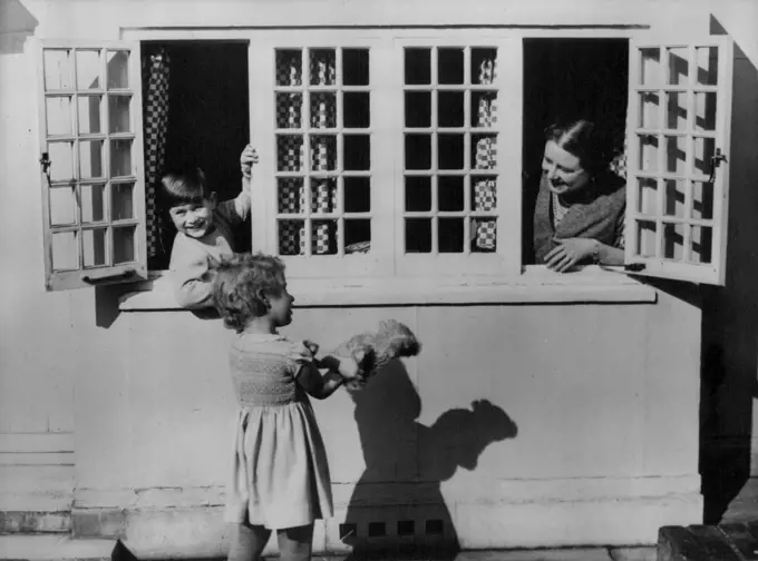 A new unpublished photograph of Prince Charles and Princess Anne.Prince Charles with the Queen Mother looking out of the window of the little Welsh House talking to Princess Anne who is showing them a glove puppet.This new picture of the Royal Children was taken at the Royal Lodge, Windsor, and is one of the many which will appear in the book published by John Murray and written by Lisa Sheridan, the royal photographer, entitled "Playtime At Royal Lodge" on Sale to the public Thursday August 12th 1954. August 07, 1954. (Photo by Paul Popper, Paul Popper Ltd.).