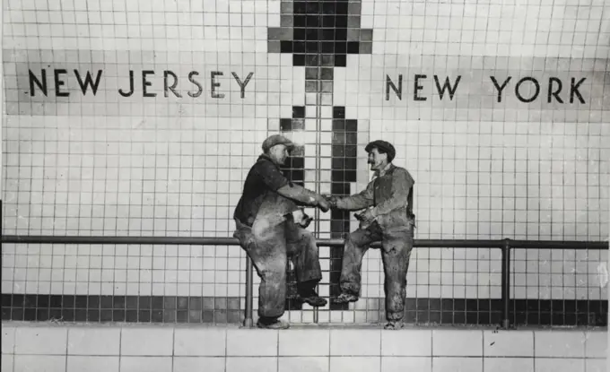 Over The State Line Under The River -- George Watson (left) of Union Hill, New Jersey, is shown shaking hands with Peter Easson of Jamaica, New York, across the New York-New Jersey state line in the new Lincoln Tunnel, that joins New York with Weehawken, New Jersey. The tunnel which runs under the Hudson River will be dedicated by officials of both states on December 21st. December 10, 1937. (Photo by Keystone).