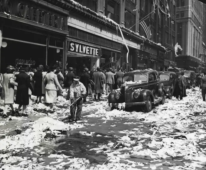 Aftermath -- ****** Sixth-street and Sixth-avenue, New York City, presented a problem to the lone street cleaner of clearing away paper tossed about by merrymakers celebrating the end of the war in Europe. July 5, 1945. (Photo by Associated Press Photo).