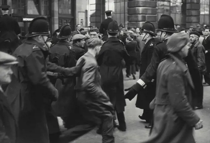 Police In Action As Dockers' Trail Ends -- A policeman uses his hands to urge a man away from the scene as foot and mounted police cleared dockers who massed near the old Bailey, London, to-day (Tuesday) when the trail of seven dockers - alleged to incite dockers to strike illegally - neared its end.Amid shouting, jeering and some scuffling, men who had gathered near the Old Bailey were driven by the police into side streets and roads away from the building. April 17, 1951. (Photo by Reuterphoto).