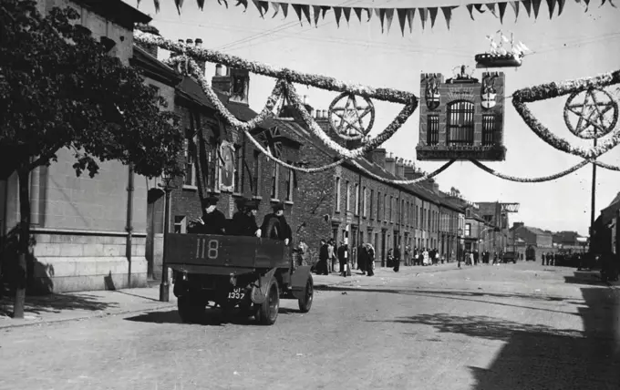 The Belfast Riots; Troops Called Out -- A police truck passing under the welcoming sign of the 12th July Orange Day arch in Belfast today, July 14.Troops were called out in Belfast last night, July 13, when rioting between Unionists and Nationalists, which began on Friday, flared up again. Today, July 14, the city was still patrolled by a thousand soldiers and policemen, and armoured cars, and every precaution is being made, for two people were killed and 60 injured in the previous night's riots. July 14, 1935. (Photo by Associated Press Photo).