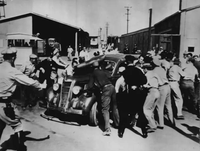 Pickets Rip Wiring From Auto -- While police seek to restrain thee, pickets at one of the Metro-Goldwyn-Mayer Studio gates halt an automobile attempting to enter the lot and rip out the ignition wires yesterday. September 28, 1946. (Photo by AP Wirephoto).