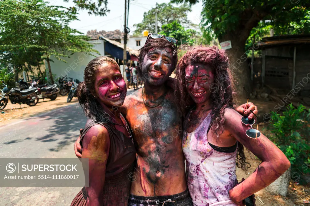 Hampi, India - April 07, 2019: happy young tourists painted in colorful pigments celebrating Holy Festival in rural village in Hanuman Halli, Karnataka, India