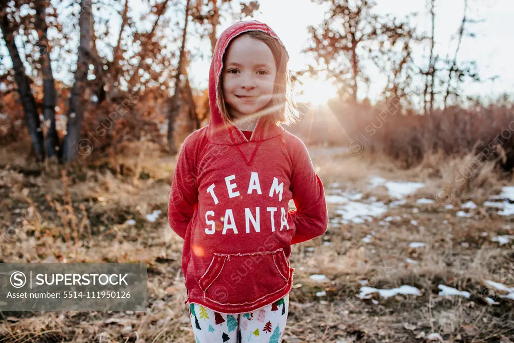 Portrait of young girl wearing a santa shirt in field with snow