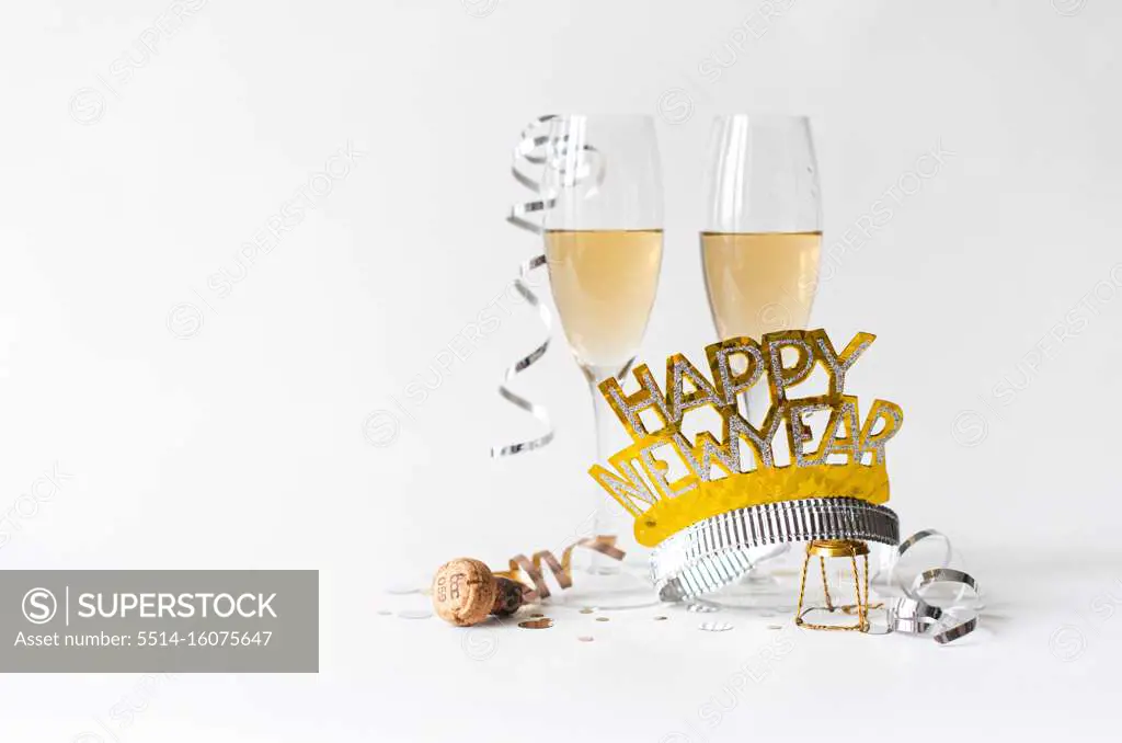 Glasses of champagne and Happy New Year hat on white background.