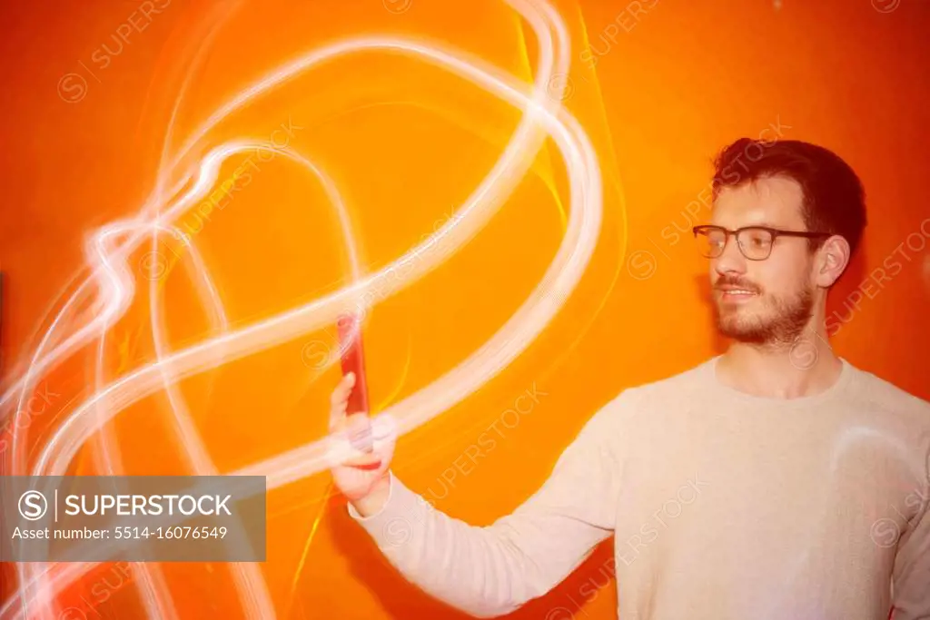 Young man looking the smartphone on a orange colored background