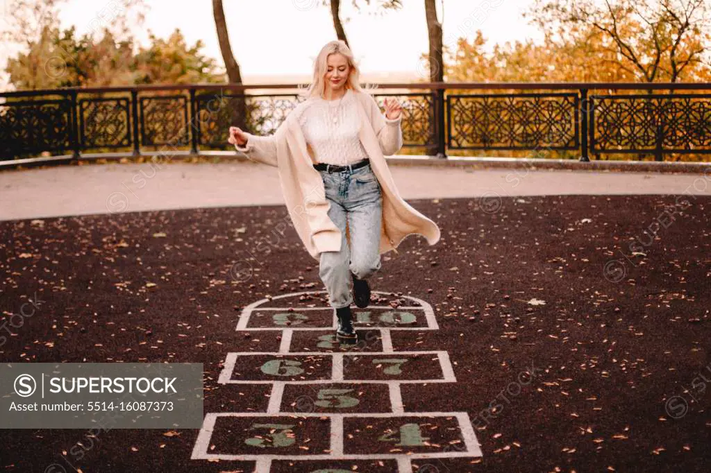 Young woman playing hopscotch in park during autumn