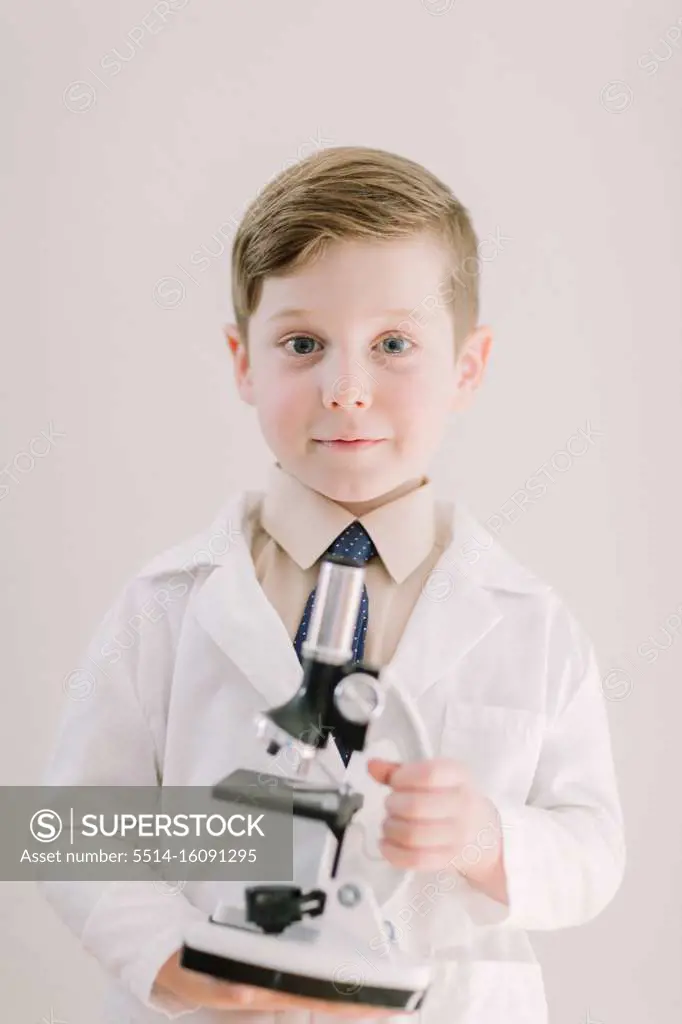 Young child holding a microscope smiling at camera