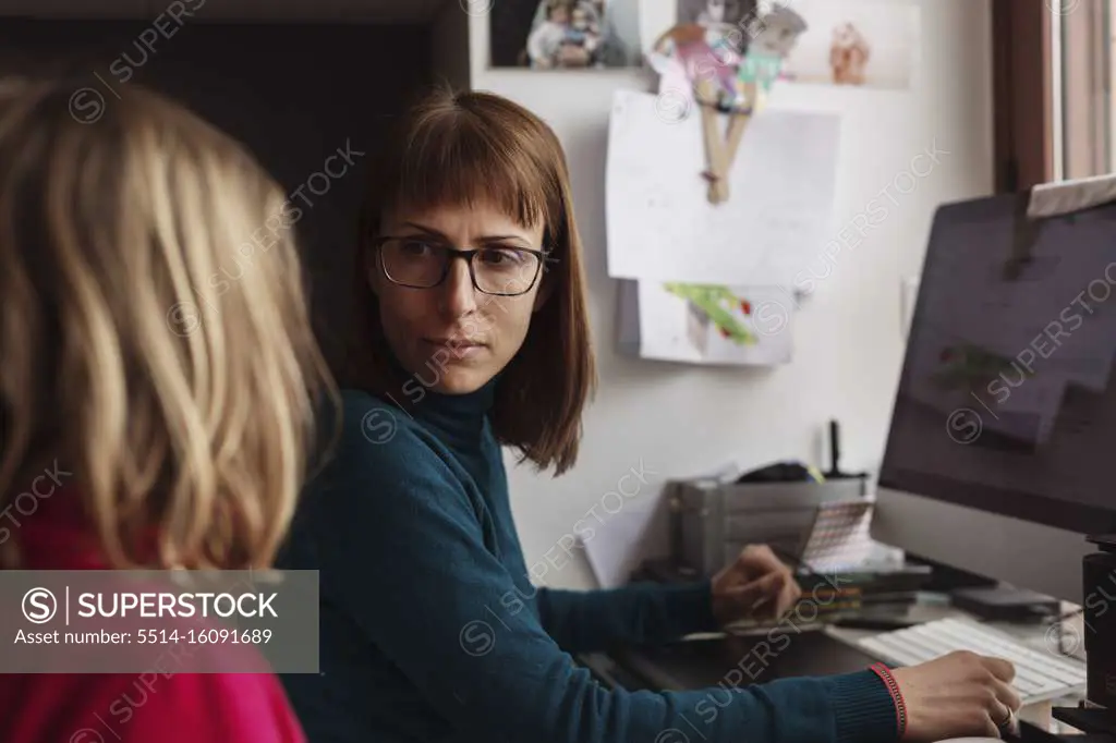 Beautiful teleworking mother is attending to her children while working on the computer in her living room
