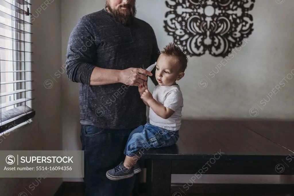 Midrange view of father taking young sons temperature at home