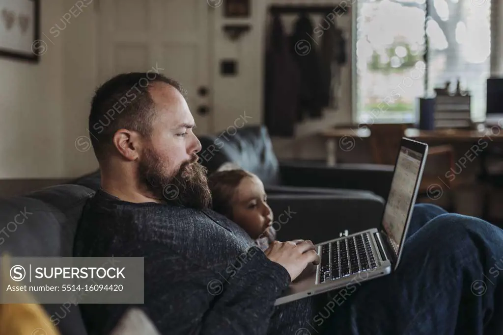 Close up of Dad working from home with young daughter