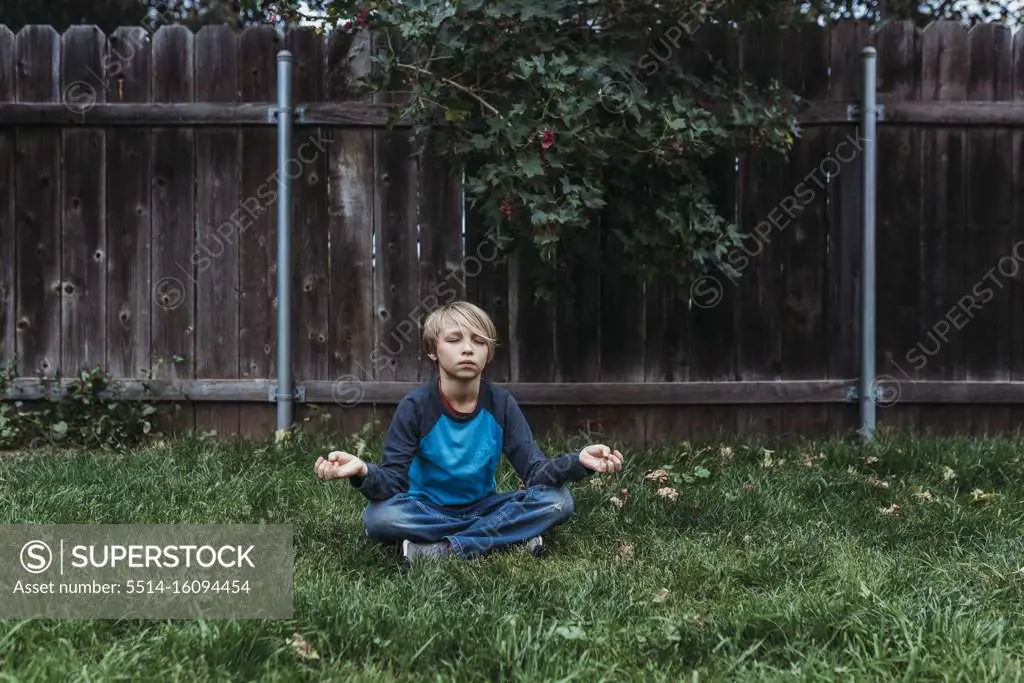 Young boy doing yoga in yard during isolation