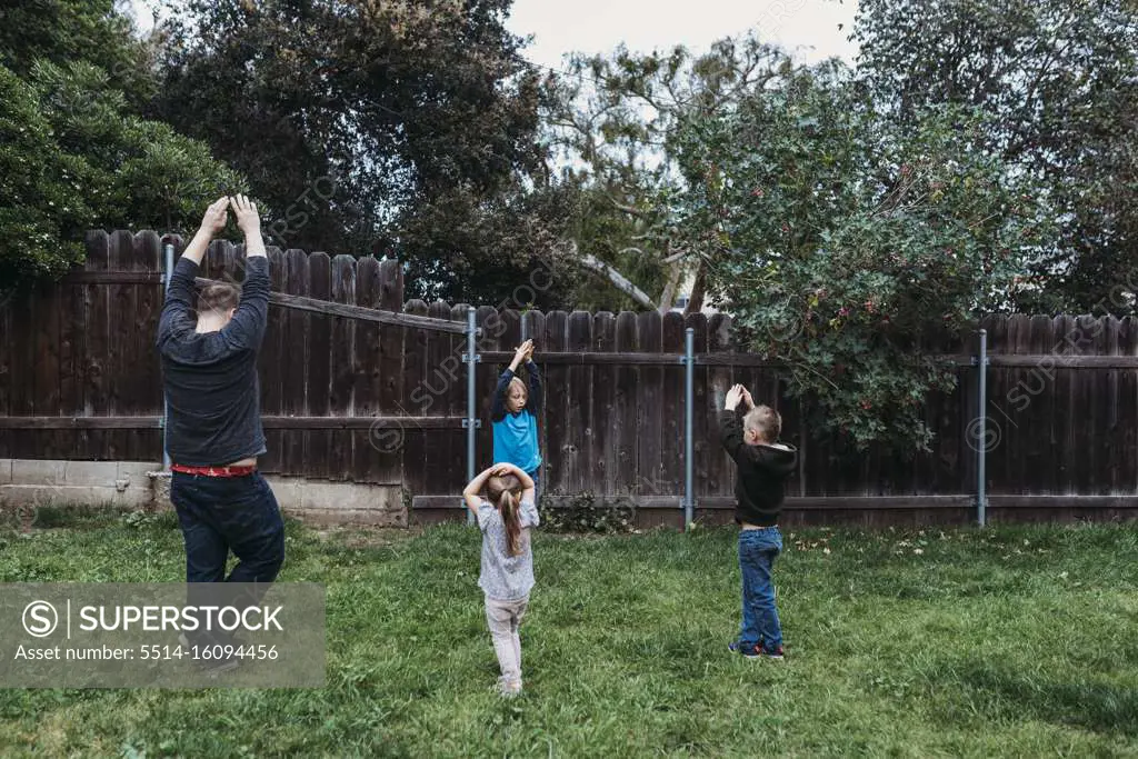 Family doing yoga together in yard during isolation