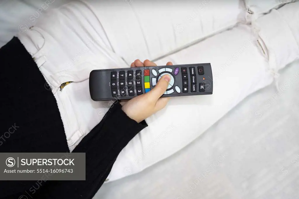 Woman using tv remote control in bed.