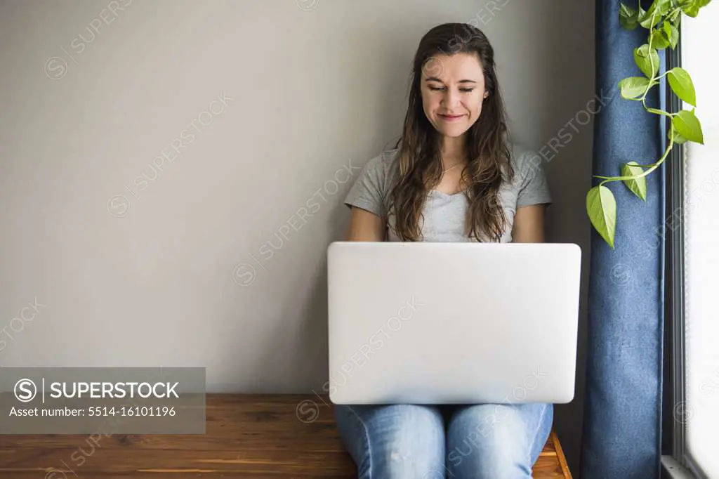 Smiling portrait of Individual Woman On her laptop at home