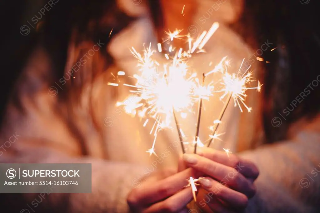 Female hands holding sparklers during Christmas in city
