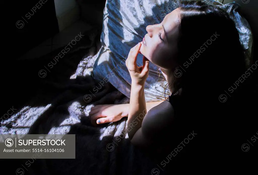young girl lying with window light and shadow on face