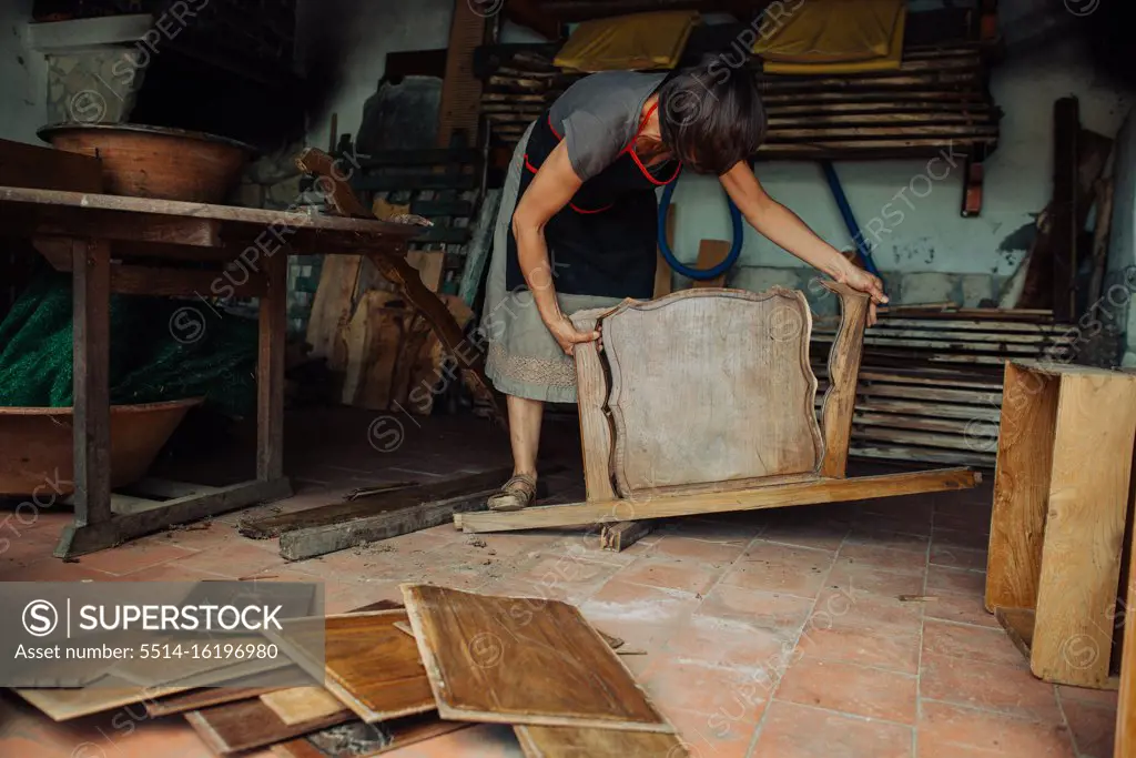 Female artisan working reusing old wooden furniture for artistic use