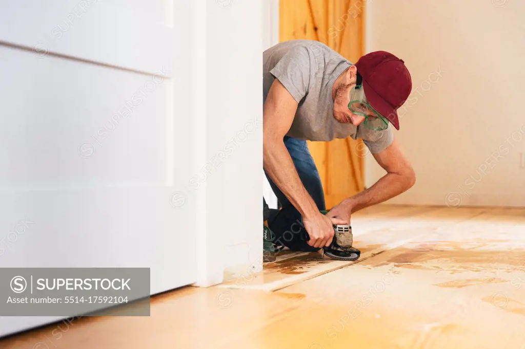 Mid adult man installing hardwood floor at home